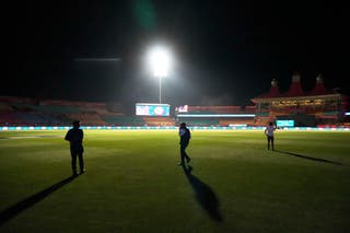 Officials walk on the playing field after the authorities asked to evacuate the stadium during the Indian Premier League cricket match between Punjab Kings and Delhi Capitals at Himachal Pradesh Cricket Association Stadium in Dharamshala